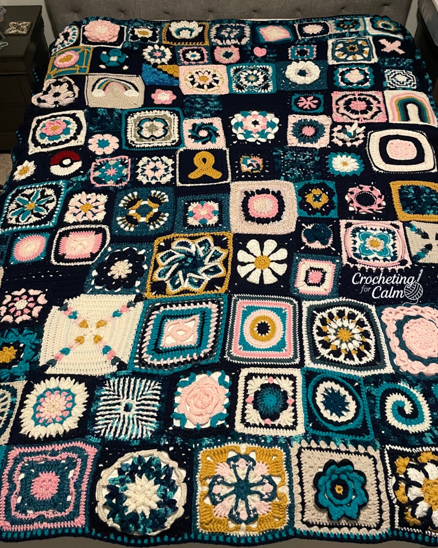 Crochet granny square sampler blanket made of dozens of squares in navy, teal, pink, and gold