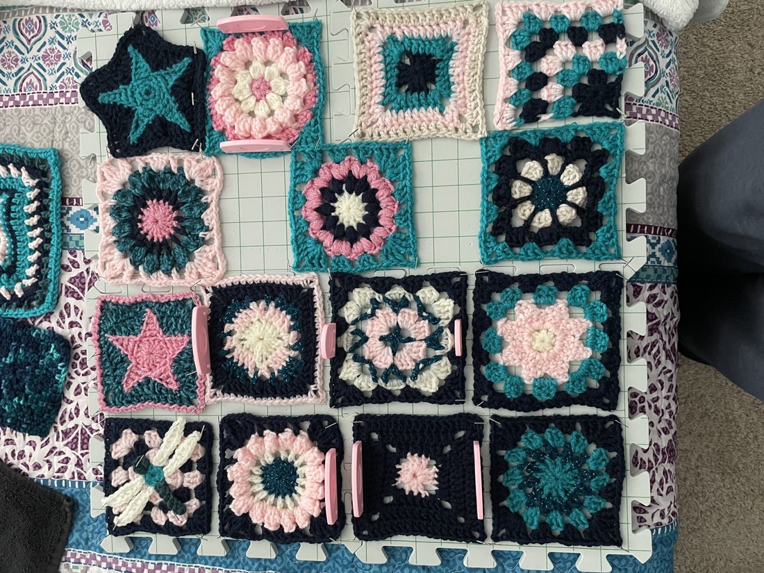 Crochet granny square set pinned out flat on a blocking mat