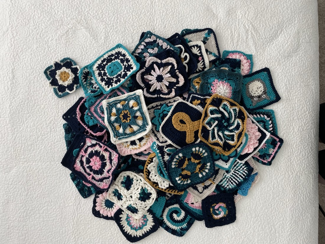 Crochet granny square pile of dozens of finished squares in assorted colors and designs